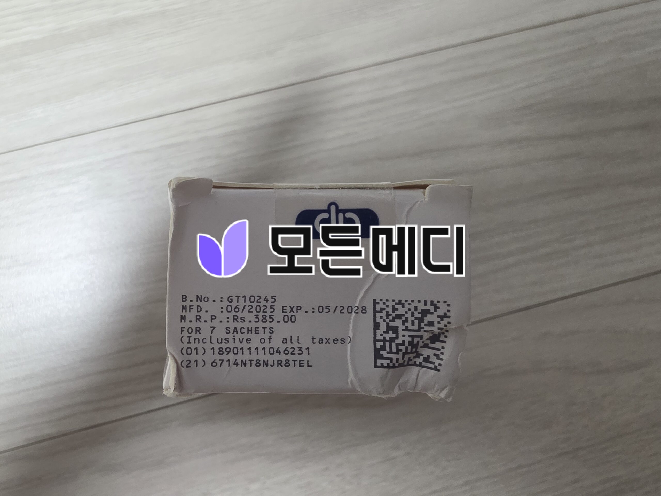 White cardboard package with a printed label showing serial B.No. GT10245, manufacture date 06/2025, expiration 05/2028, plus a QR code and a purple logo.