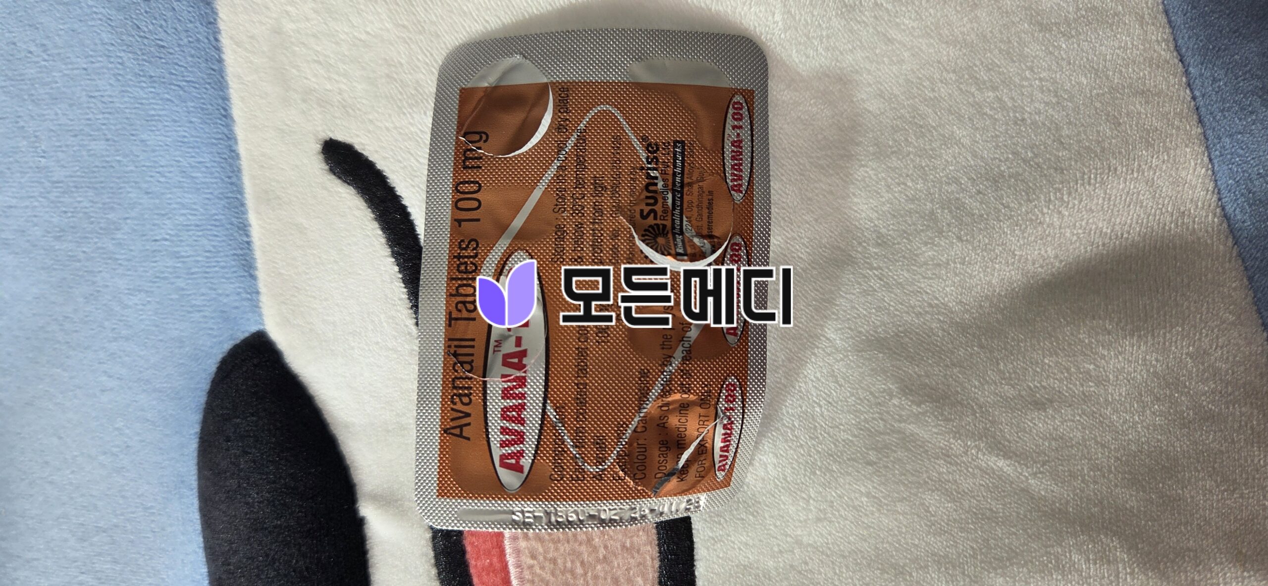 Orange blister-pack medication on a soft blanket, with pills partially removed from the foil.