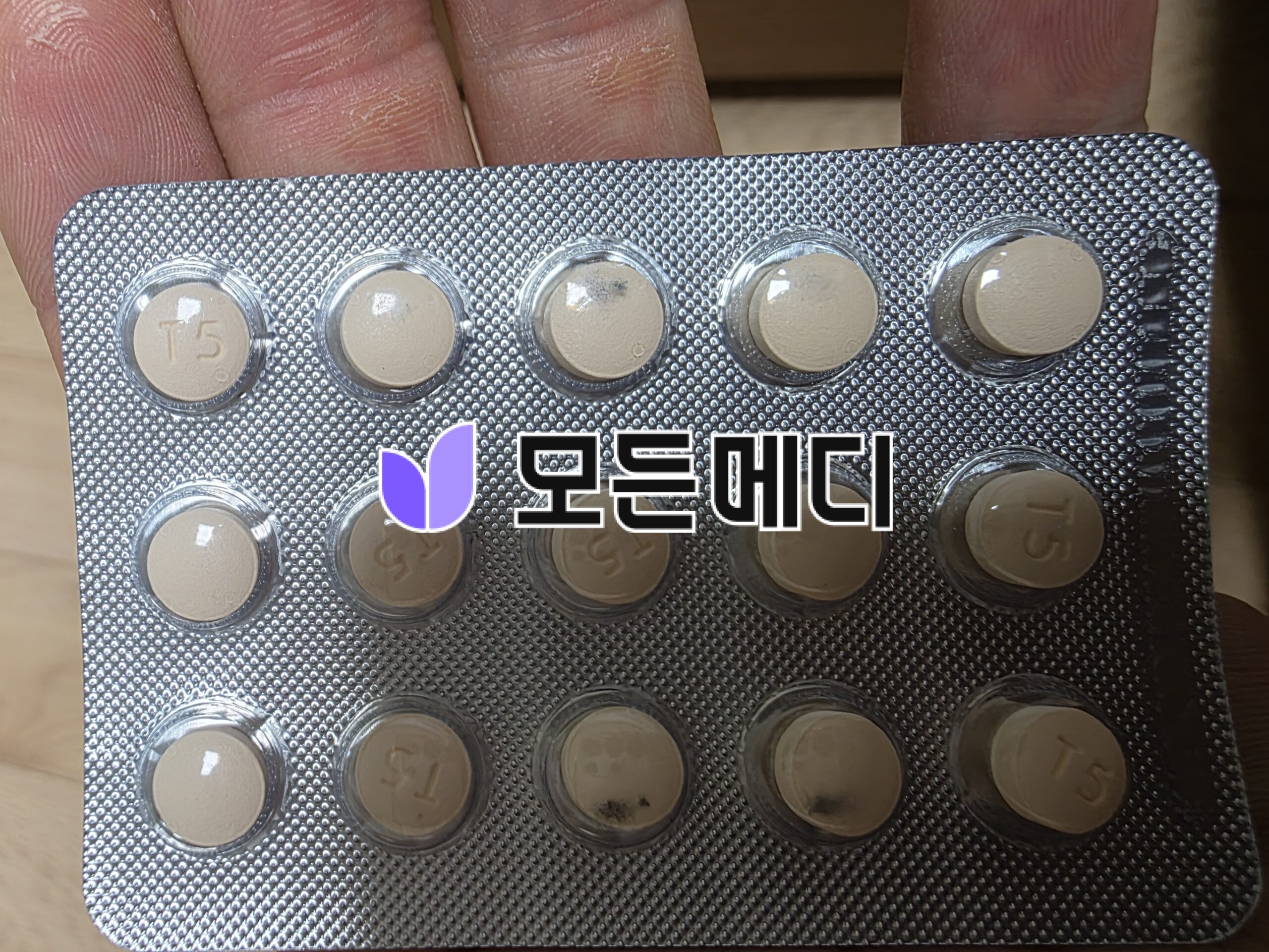 Blister pack with row of beige round tablets, one corner showing Korean branding on the packaging.