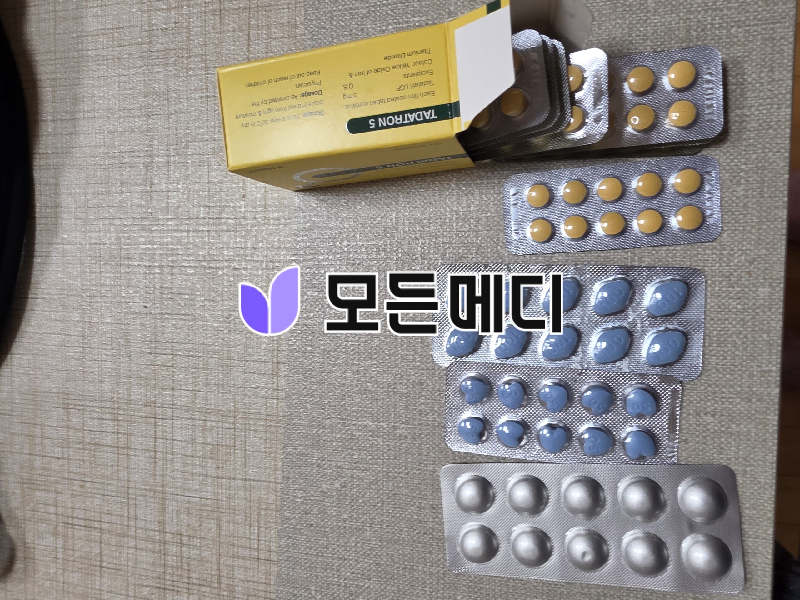 Blister packs of yellow and gray pills with a yellow medicine box on a textured wooden surface