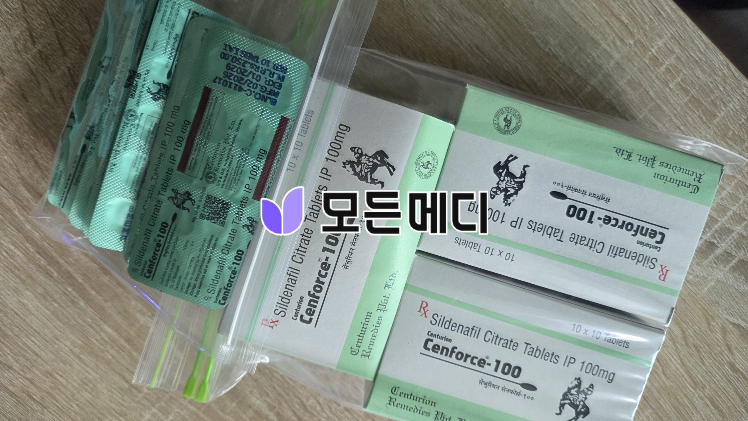 Green and white Cenforce-100 sildenafil citrate boxes and blister packs on a wooden surface.
