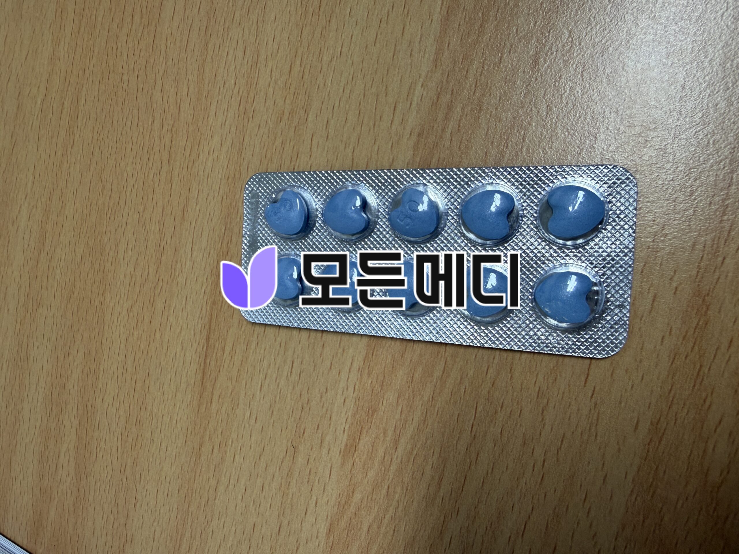 Blister pack with six blue round tablets on a wooden table surface.